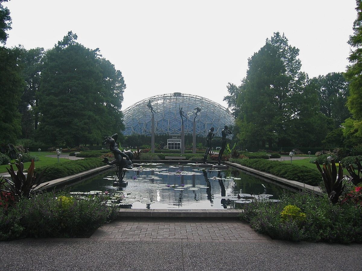 The Climatron geodesic dome rising behind a lily pond and sculptures at the Missouri Botanical Garden